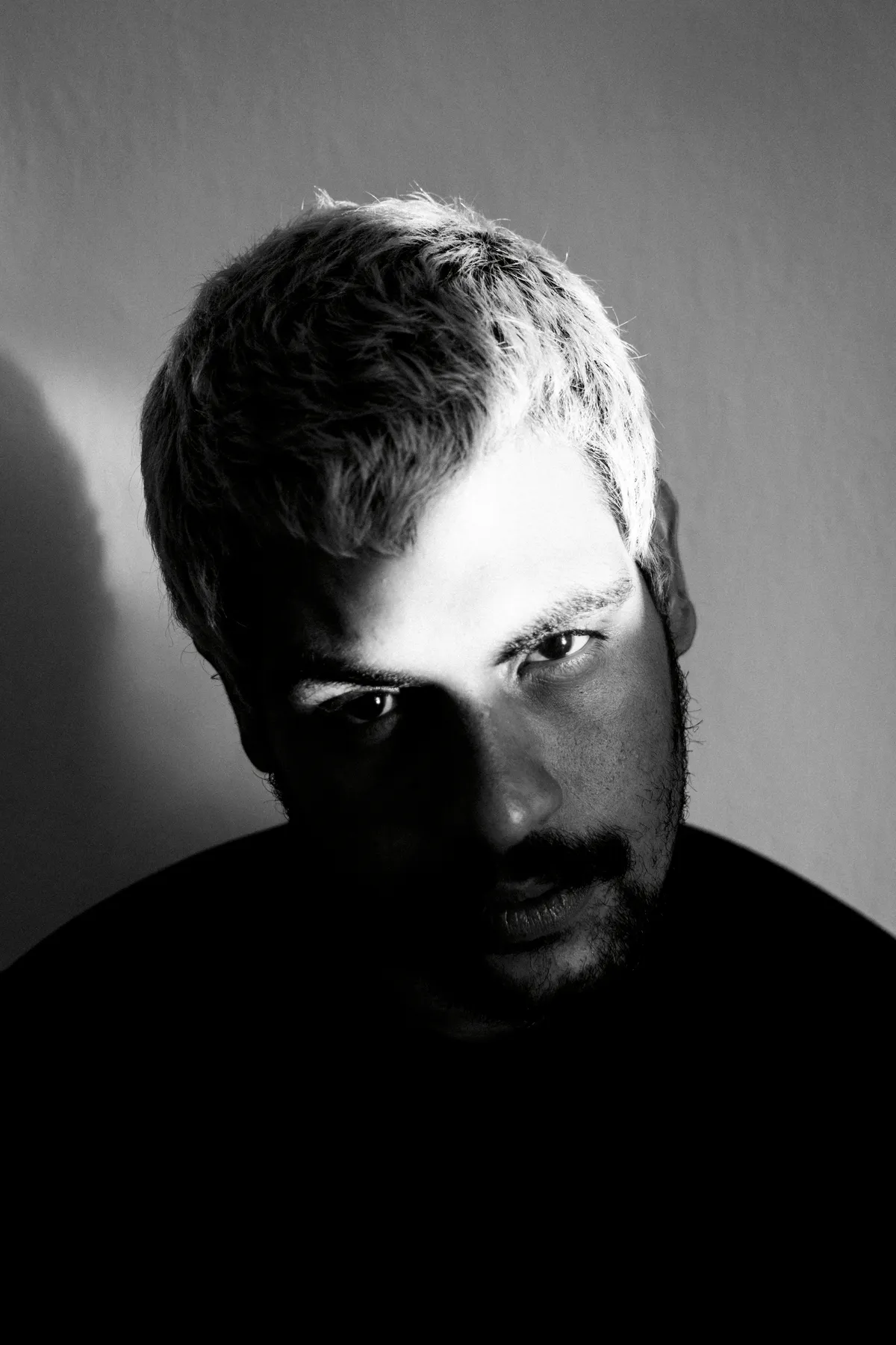 High-contrast monochrome headshot, half in shadow