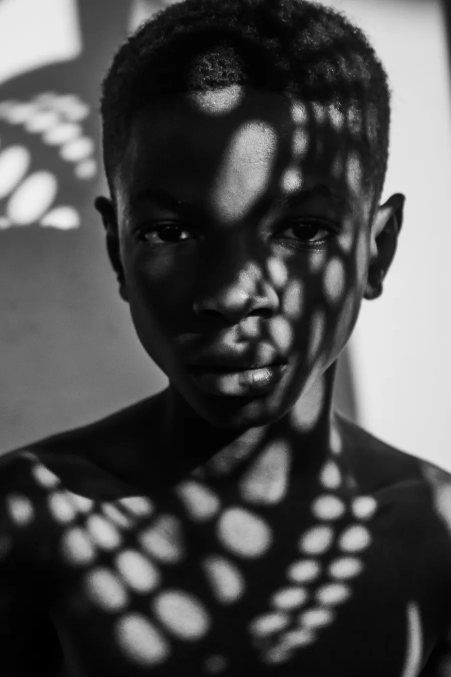 Studio portrait with hard shadow patterns across the face