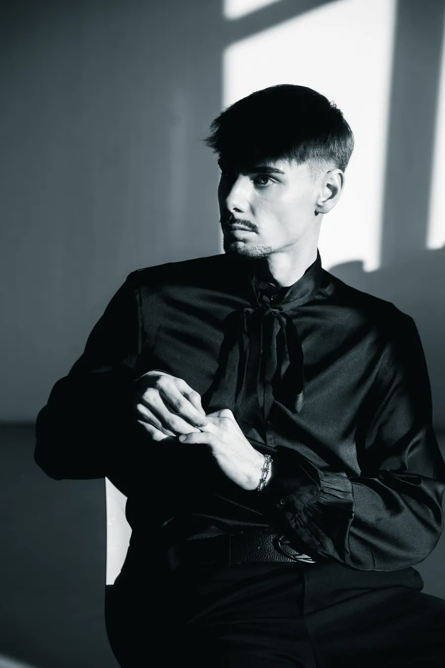 Studio portrait in black clothing against a pale wall