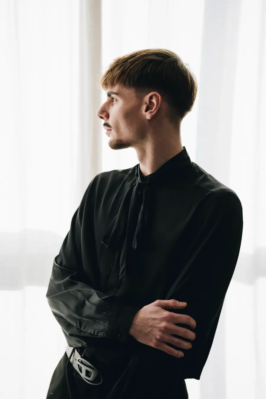 Profile portrait at a window in dark clothing