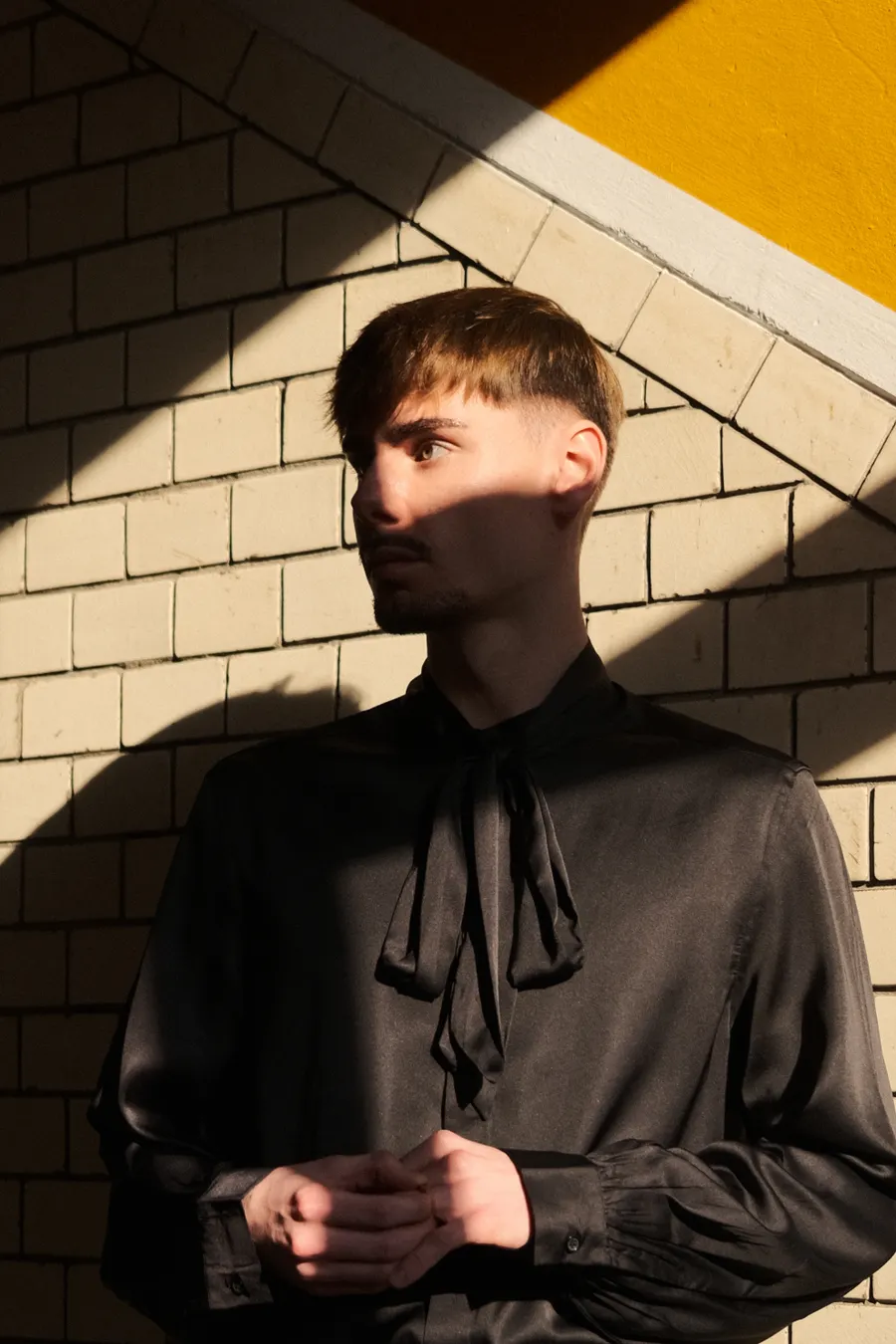 Portrait with dramatic shadow bars across a tiled wall