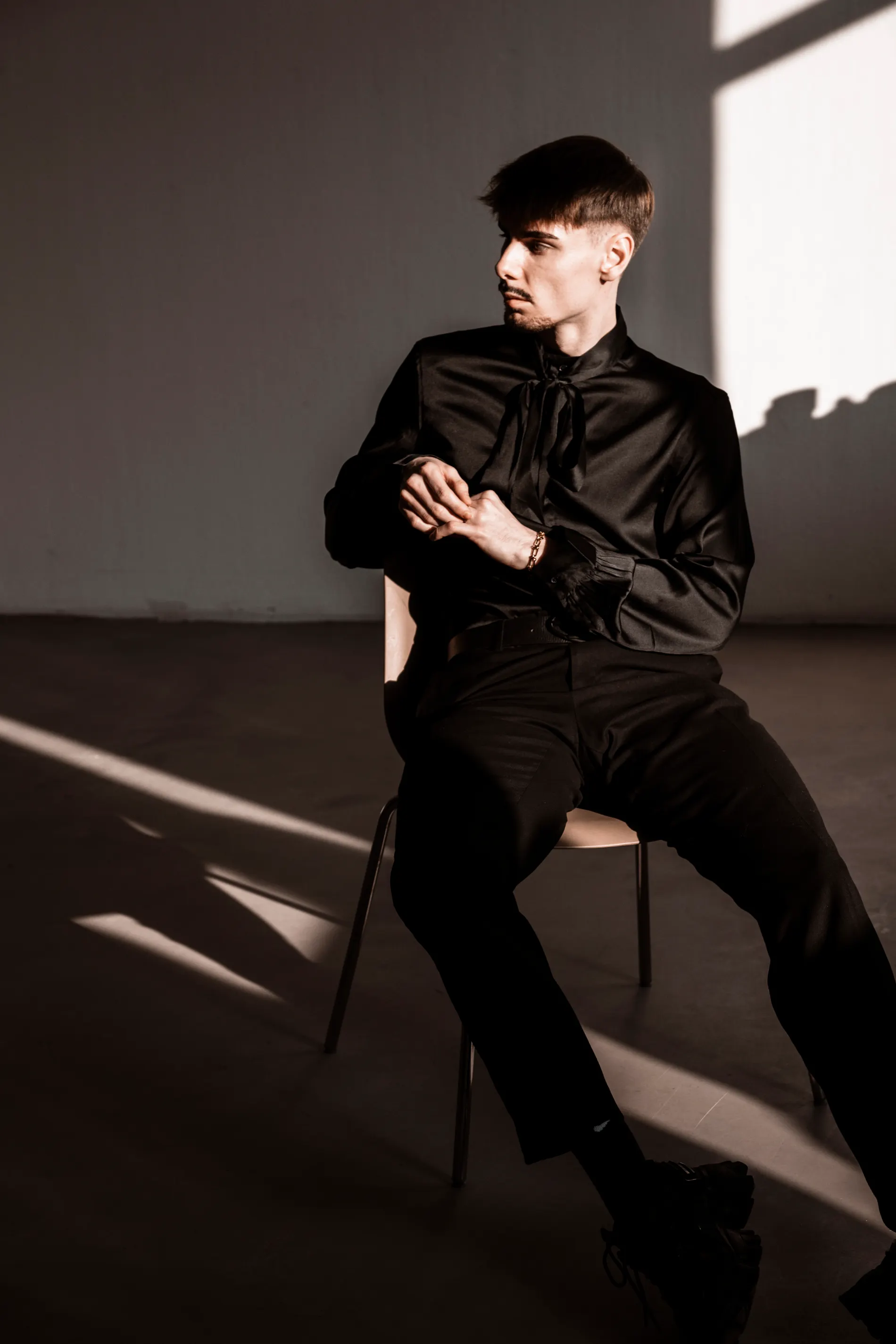 Elias Vance seated in a shaft of hard studio light, waiting for a take