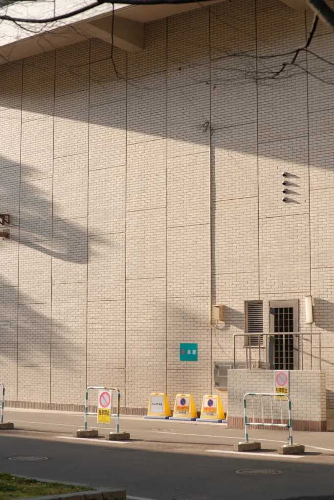 Plain building corner with afternoon shadow across the render