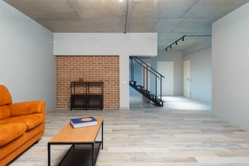 Sitting room with a low sofa beside a painted brick stair wall
