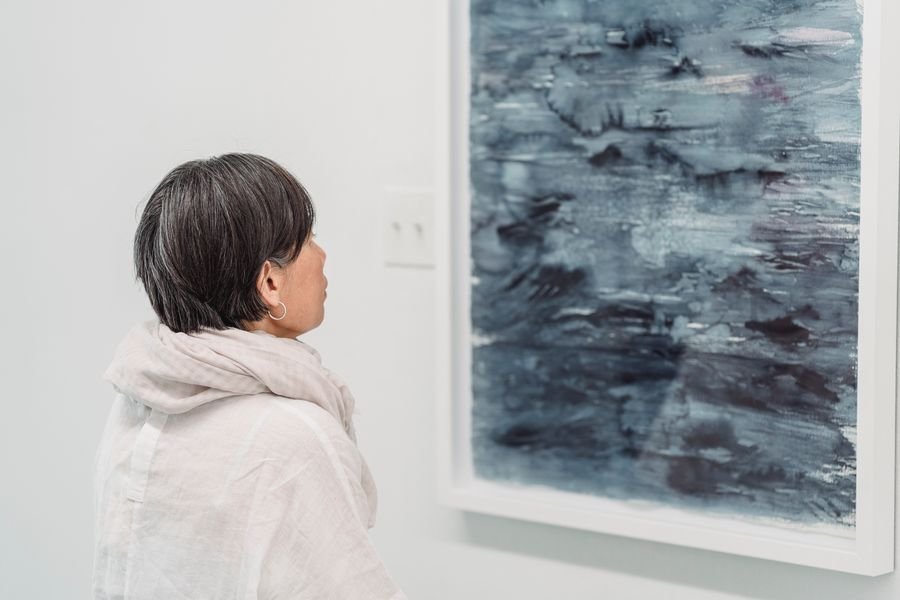 A visitor studying a large abstract painting in a white gallery room