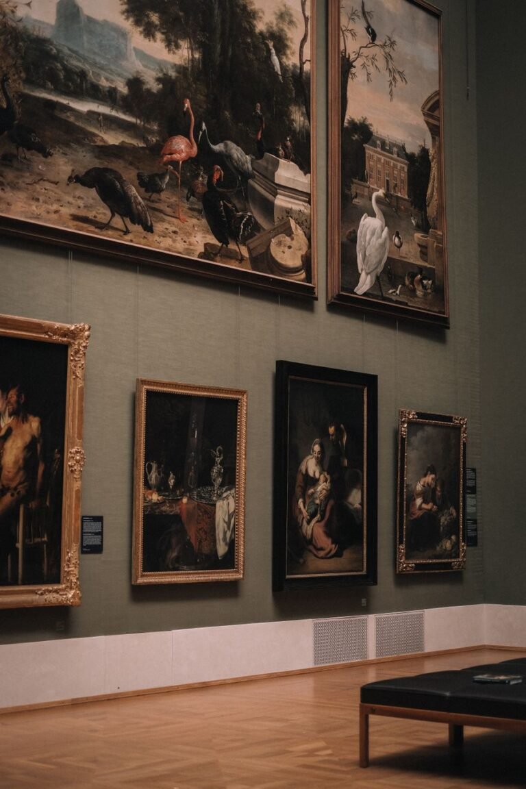 Classical paintings hung salon-style on deep green walls