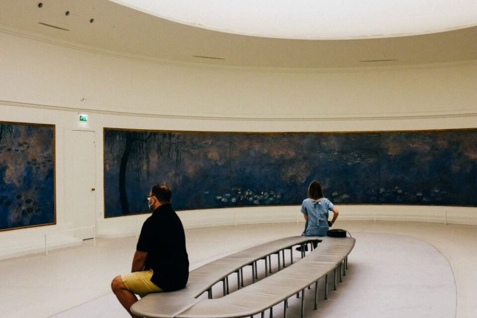 Round gallery with a glass ceiling and visitors seated on a curved bench