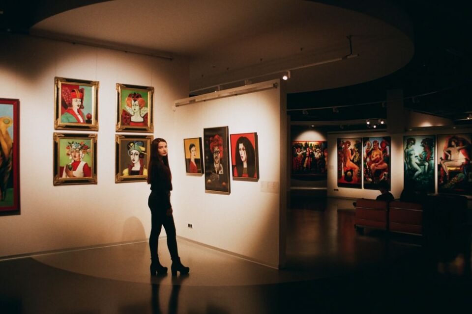 A visitor standing among colourful paintings in a contemporary exhibition