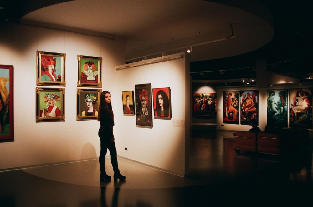 A visitor standing among colourful paintings in a contemporary exhibition