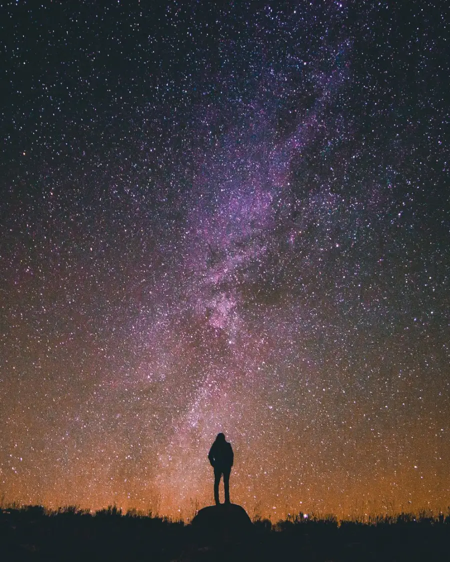 A lone figure standing beneath the Milky Way at night
