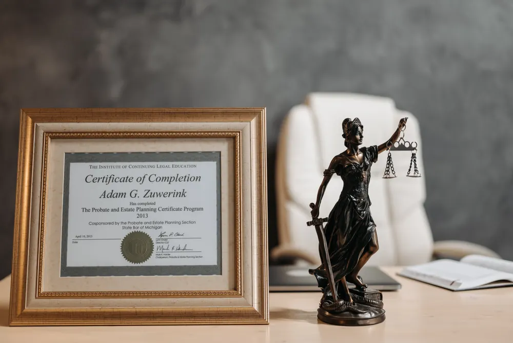 Framed legal certificate beside a Lady Justice figurine on a desk