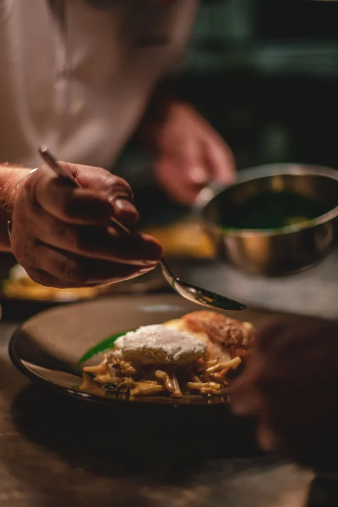 Chef finishing a plated dish with sauce