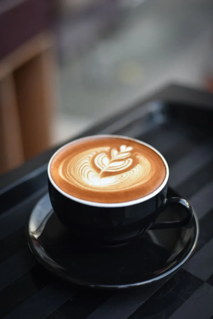 Cappuccino with rosetta latte art in a black cup