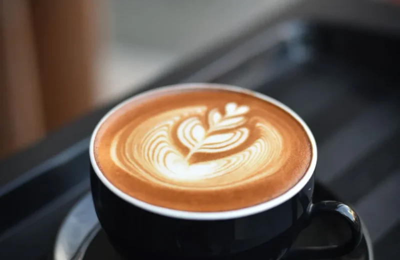 Cappuccino with rosetta latte art in a black cup