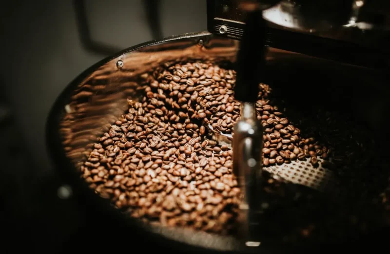 Freshly roasted coffee beans turning in the cooling tray of a drum roaster