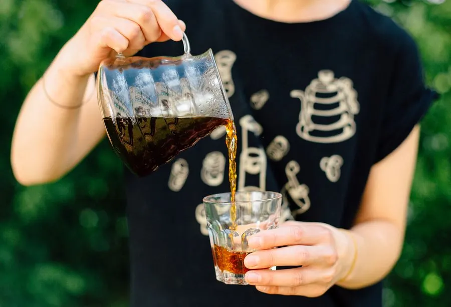 Barista pouring coffee from a pitcher into a glass