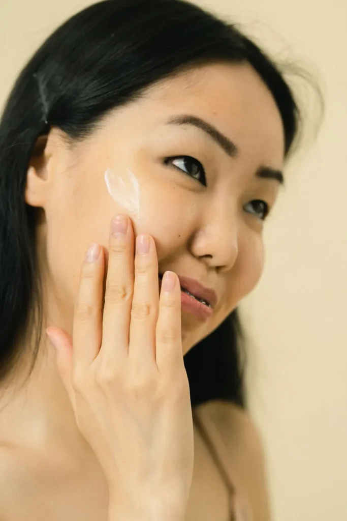 Smiling woman massaging cream into her face