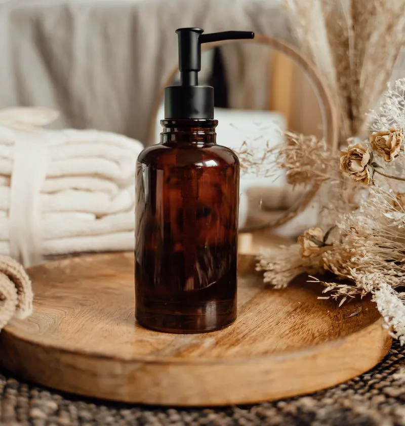 Glass body oil bottle with towels and dried flowers