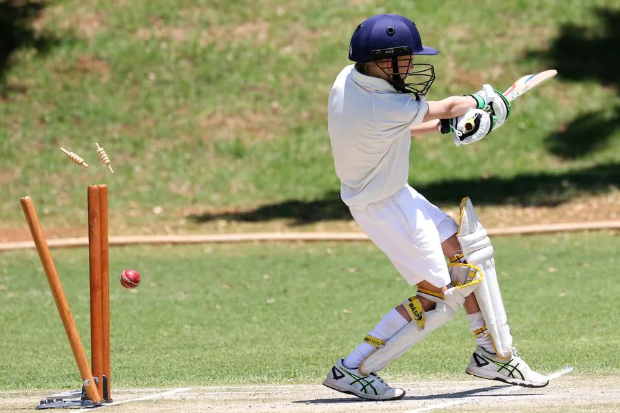 Young cricketer in full gear playing a sweep shot