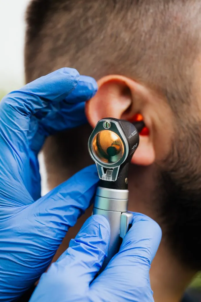 Gloved hands performing an ear exam