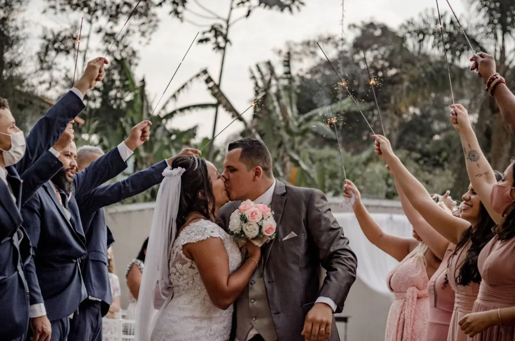 Bride and groom kissing under sparklers held by guests