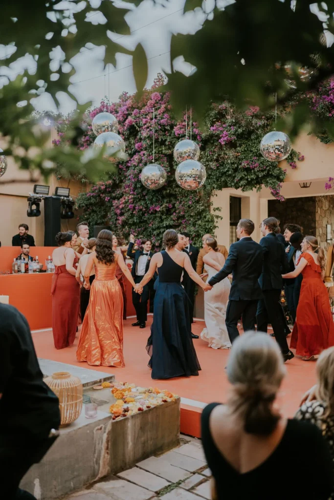 Guests at an outdoor wedding reception with floral backdrop