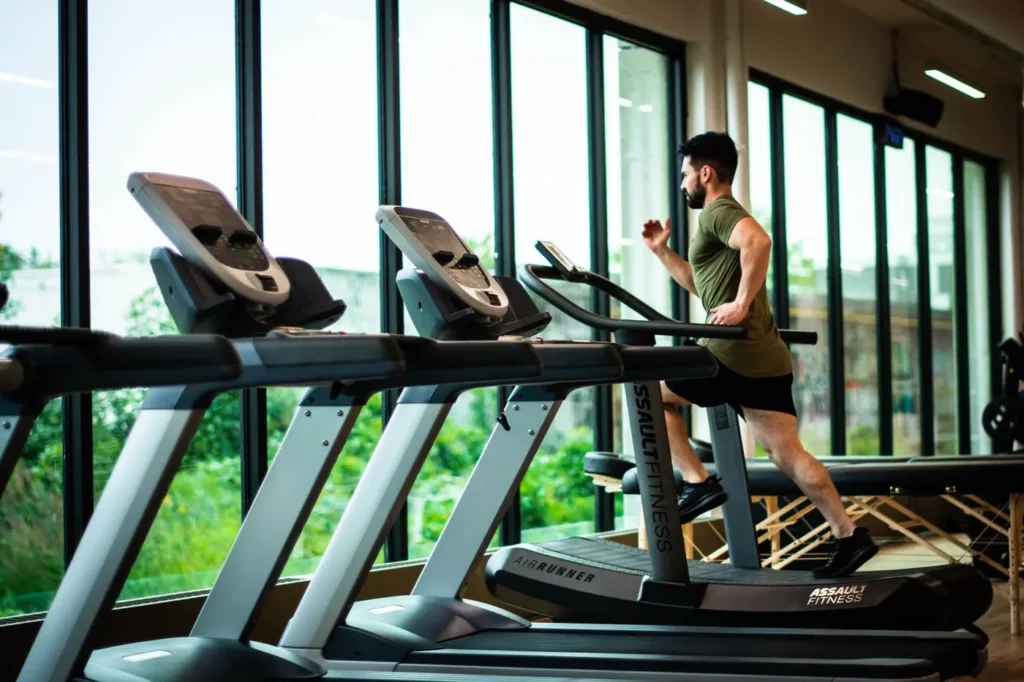 Man running on a treadmill by the gym windows