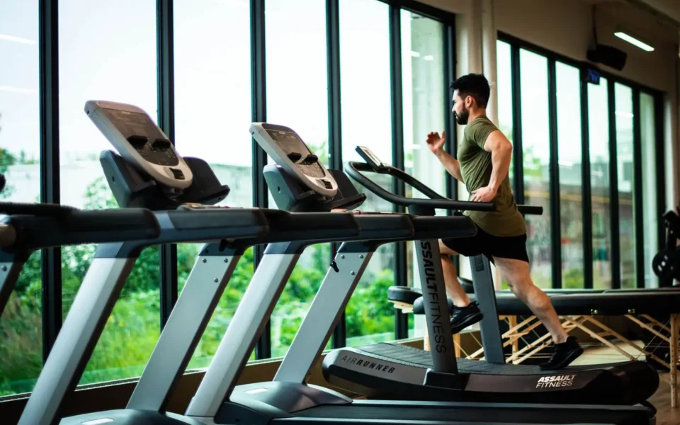 Man running on a treadmill by the gym windows