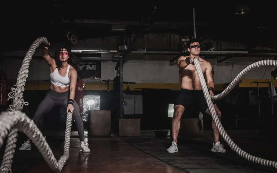 Two athletes training with battle ropes