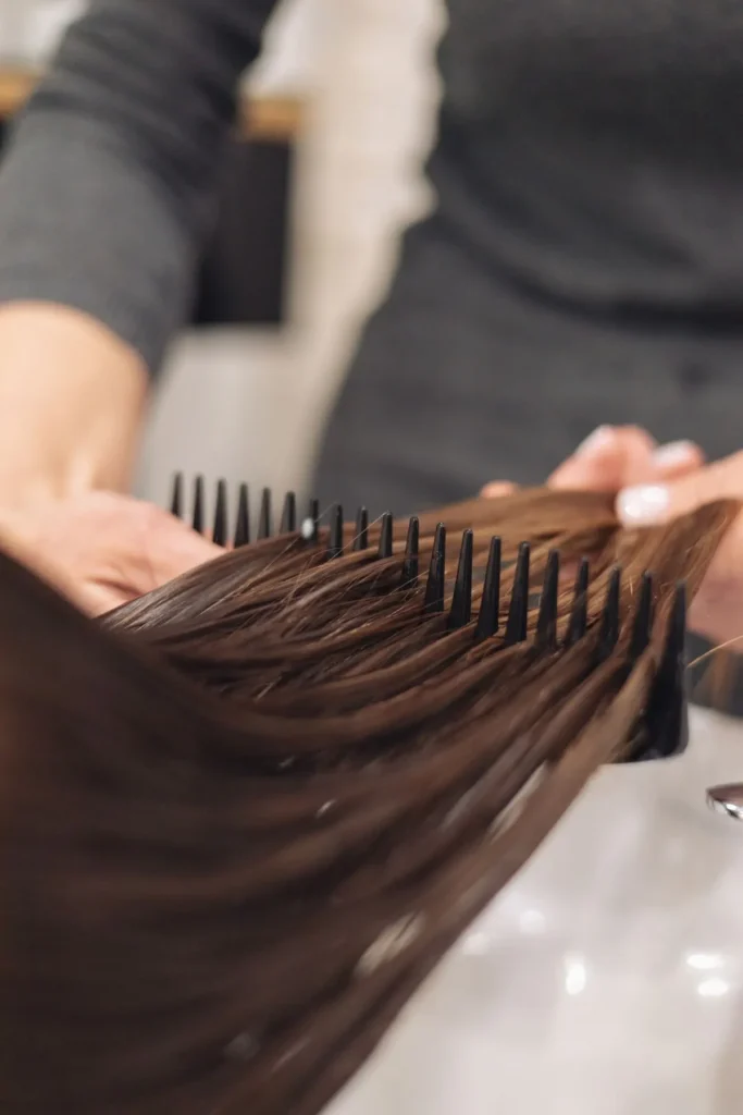 Stylist combing glossy hair after a keratin treatment