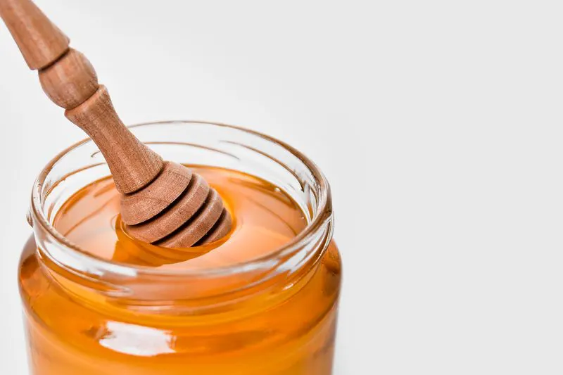 Clover honey jar with dipper on white background