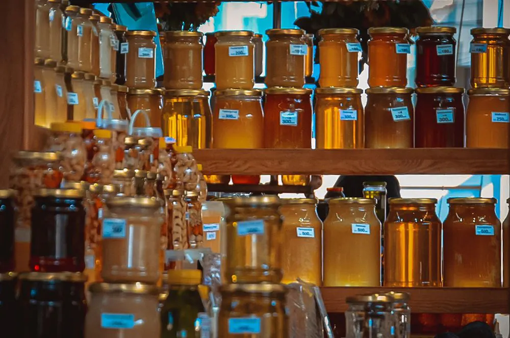 Honey jars of many shades on wooden shelves