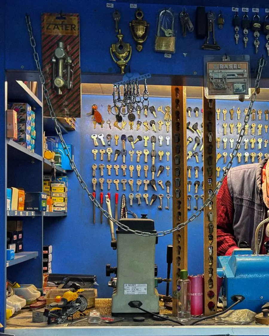 Experienced keymaker cutting a key in a workshop full of locks