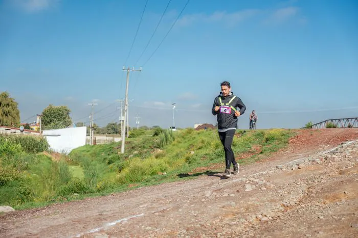 Athlete wearing a race bib running on a dirt path