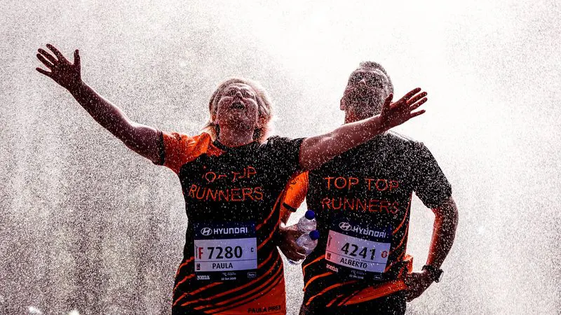 Two runners celebrating under a cooling spray