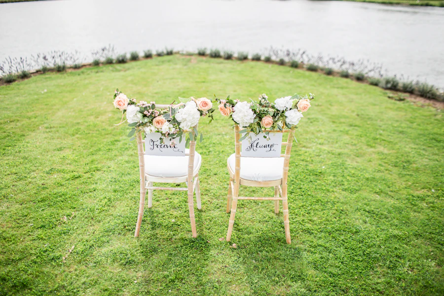 Two decorated wedding chairs on a lawn