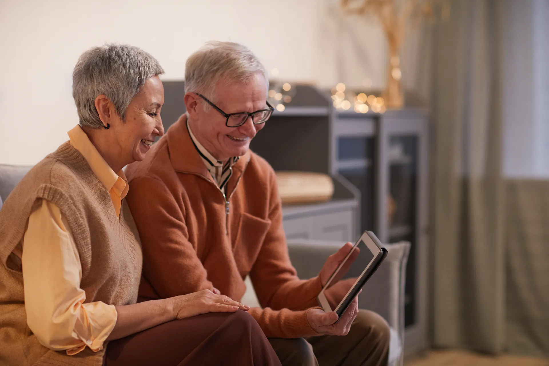 Senior couple smiling while looking at a tablet