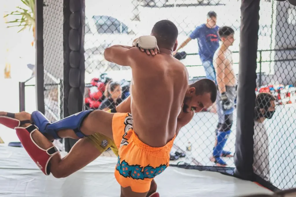 MMA fighters sparring inside a training cage