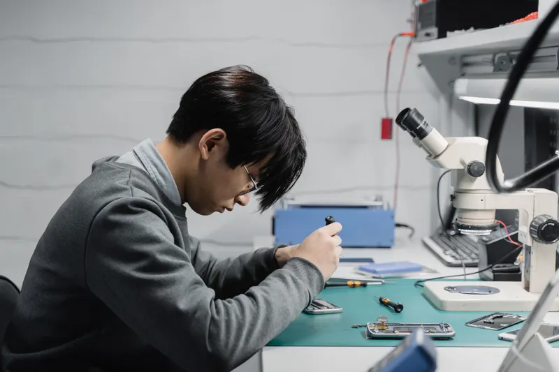 Technician working under a microscope on a phone