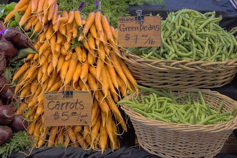 Bunches of organic carrots and green beans at a market stall