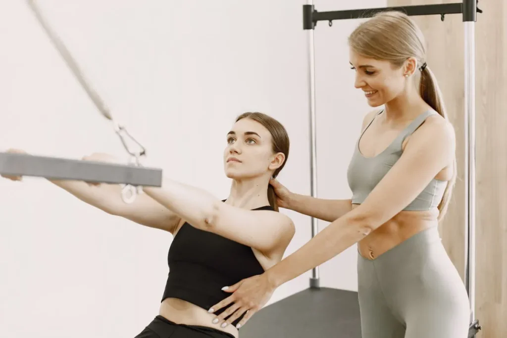Instructor correcting a client during a Pilates class