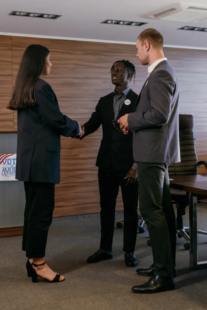 Three professionals shaking hands across a table in a meeting room