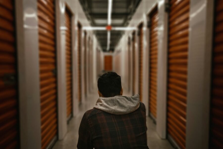 A wide indoor corridor lined with roller-shutter storage unit doors