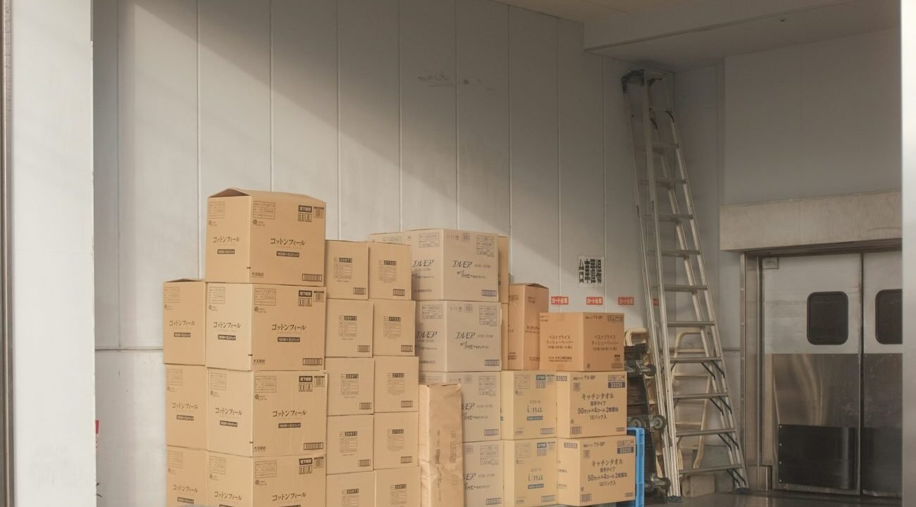 Sealed cardboard cartons stacked neatly on a pale tiled floor