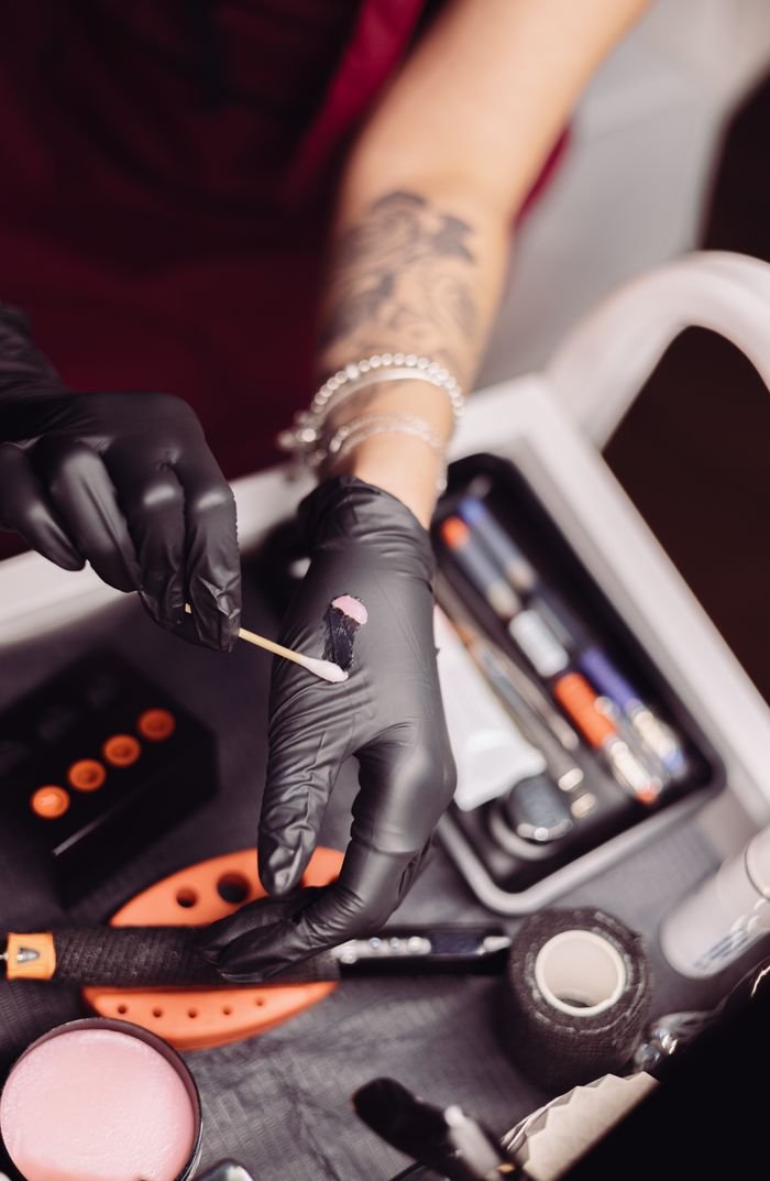 Gloved hands preparing sterile tattoo tools