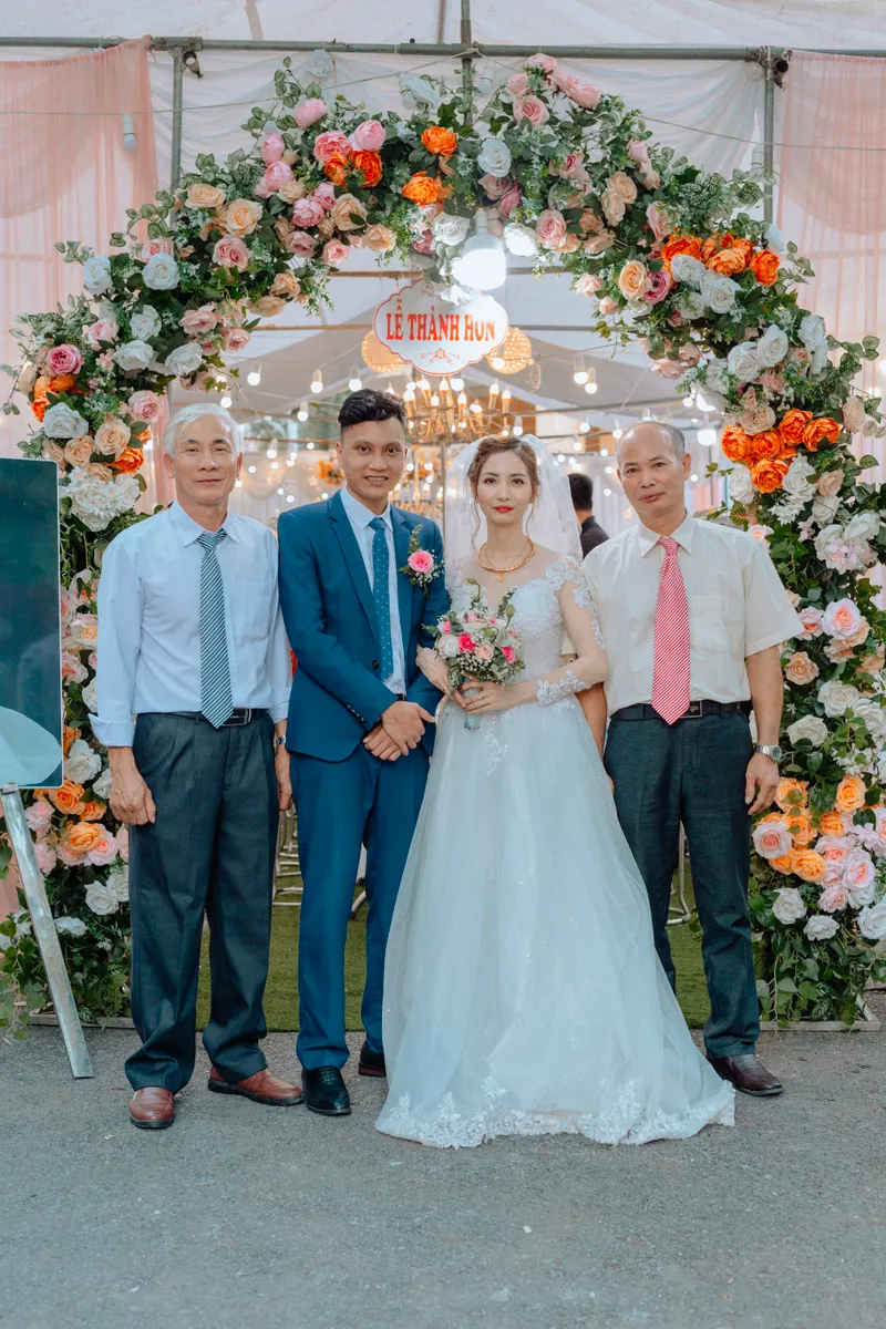 Bride and groom with family under a floral arch