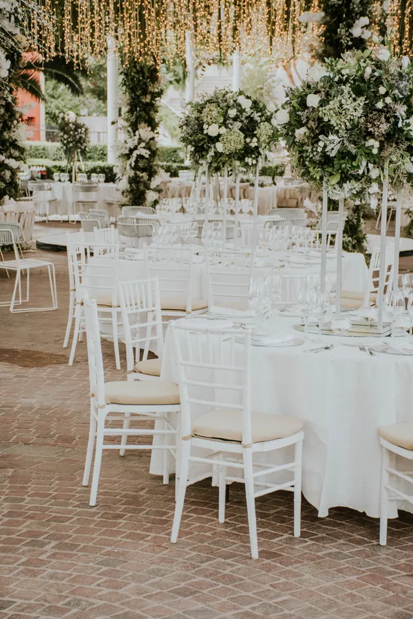 Outdoor reception with white chairs and florals