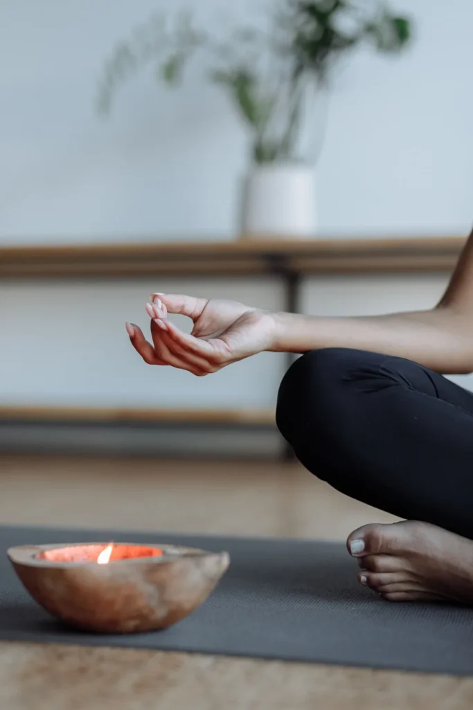 Hand resting in a meditation mudra beside a lit candle