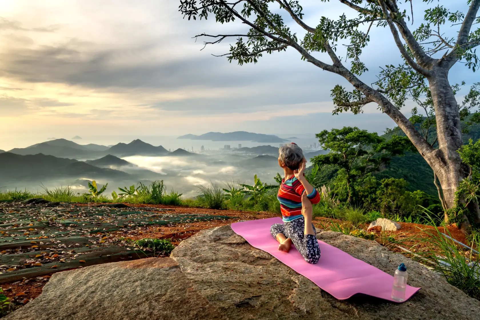 Woman practising on a mat above a misty valley