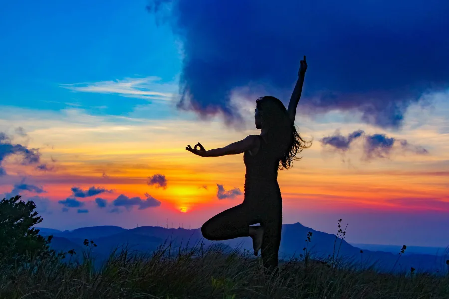 Silhouette in a yoga pose against mountains at sunset